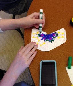 A student draws a pattern on a kaleidocycle.